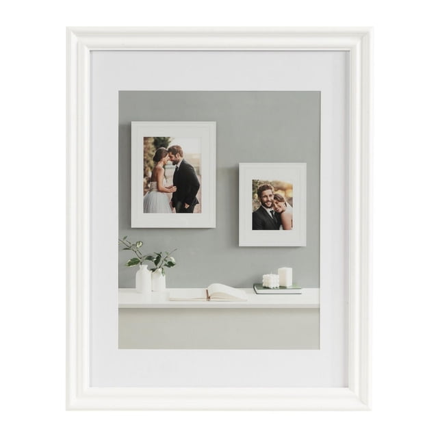 hometrends Leno Cadre Photo en Blanc avec Fini Peint, Présentant Deux Petits Cadres Blancs avec des photos sur un Mur Gris au-Dessus d'Une Tablette Blanche Tenant un vase Blanc avec de la Verdure, un Livre Ouvert et des Bougies, Idéal pour Exposer des Souvenirs Chers et Adapté pour Offrir.