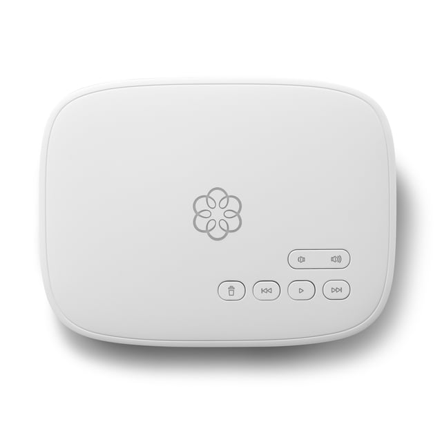 Ooma Phone Genie VoIP Internet Home Phone Service base station in a sleek white design with a compact rectangular shape. The device features a central Ooma logo and control buttons for volume, playback, and voicemail management. Designed to connect to your home internet, it provides an affordable landline phone replacement with unlimited calling in the U.S., Canada, and Mexico, advanced features like robocall blocking, voicemail-to-email forwarding, and Pure Voice HD technology for clear calls. Suitable for home use with easy setup by connecting to your internet and plugging in a home phone.