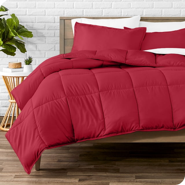 Bare Home Goose Down Alternative Comforter Set - 3 Piece Set - King/Cal King, Red. This bedding set includes a red ultra-soft down alternative comforter measuring 106 inches by 94 inches and two matching pillow shams measuring 20 inches by 36 inches. The comforter features box stitching to prevent fill shifting and is made from hypoallergenic microfiber polyester, offering breathable, all-season comfort. Displayed on a wooden bed frame in a modern bedroom setting with a white brick wall and a side table with decor.