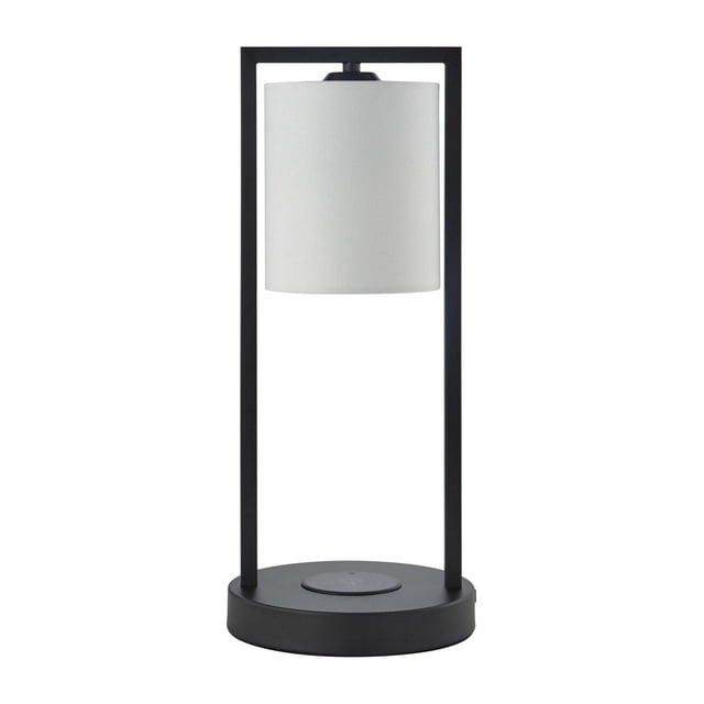 hometrends Table Lamp with USB Port & Wireless Charger featuring a black metal open frame base and white fabric cylindrical shade, standing 17 inches tall with a built-in Qi wireless charging pad and 5V 1A USB port on the round base, suitable for bedrooms, offices, or rec rooms.