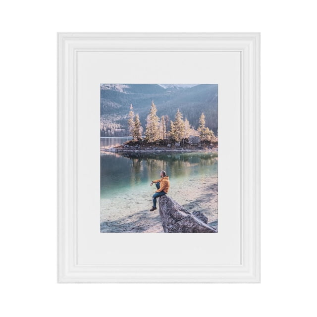 hometrends Leno Picture Frame in white painted finish displaying a vertical photo of a person in an orange jacket sitting on a rock by a clear lake with pine trees and mountains, ideal for wall frame display and photo showcasing in home décor.