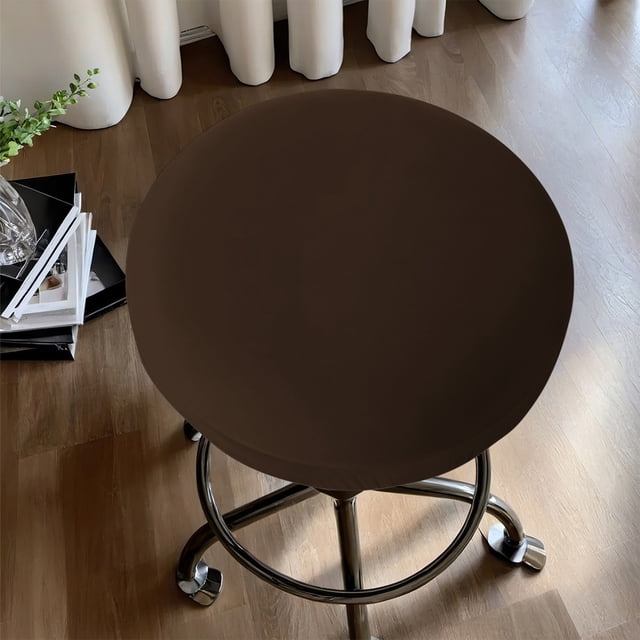 Czzoypi Housses de Siège de Tabouret de Bar Rondes Extensible Housses de Tabouret de Bar Rondes Lavables Housses de Siège de Tabouret de Bar Couleur Café, Affichées sur un Tabouret de Bar Rond avec une base Chromée. Fabriquée en polyester en Soie de Lait Élastique, la Housse Offre un Ajustement Serré, une texture Douce et une protection contre les Déversements. Convient aux Tabourets de Bar dans les Cuisines, les Salles à Manger Ou les bars à la Maison. le Cadre Comprend un Plancher de Bois et une Déco à Proximité, comme des Livres et une Plante.