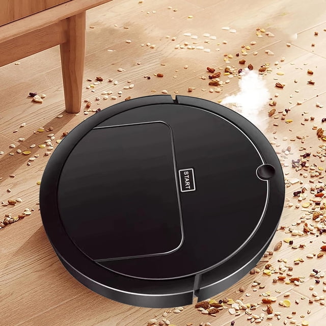 EGNMCR Three In One Intelligent Sweeping Robot Vacuum Cleaner Rechargeable in black, positioned on a wooden floor with visible debris. The robot features a 'Start' button and emits a humidification spray while cleaning. Designed for sweeping, suction, and mopping, it is lightweight and suitable for tight spaces like under sofas and beds.