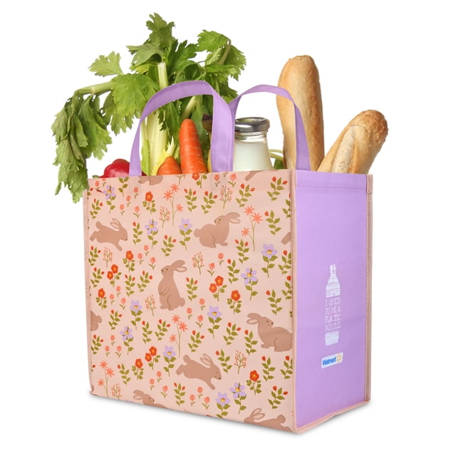 2026 Easter Walmart reusable grocery bag with pastel pink front panel decorated with brown bunny and floral patterns, lavender side panels featuring eco-friendly messaging, and lavender handles. The bag holds celery, carrots, a glass milk bottle, and two baguettes, made entirely from recycled plastic bottles for sturdy, eco-conscious grocery use.