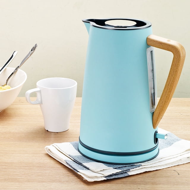 QUETO Electric Kettle 1.7 L Soft Touch Gray with a wooden handle and stainless steel construction, shown in a light blue finish. Ideal for tea and coffee preparation, it features three-dimensional surround heating, automatic shut-off, and a maximum power of 1800W. Positioned on a wooden countertop with a white mug and bowl nearby.