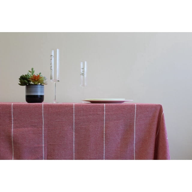Fabstyles Fouta 100% Cotton Stripe Table Cloth in muted red with thin white vertical stripes on a rectangular table, styled with two clear champagne flutes and a small black and white striped pot holding green and orange succulents, ideal for indoor dining and entertaining.
