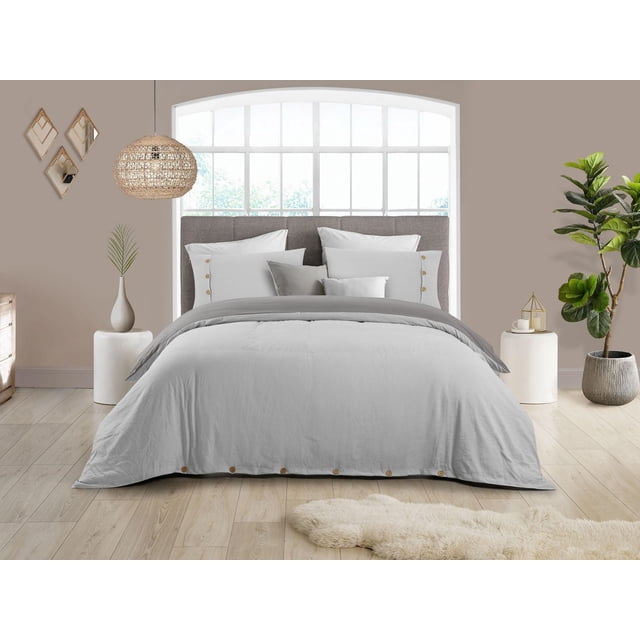 Reversible Natural Crinkle Fabric Ultra Soft Solid Duvet Cover Set in light grey with button closure on a queen-size bed with grey upholstered headboard, including matching pillow shams and decorative cushions, set in a bright room with light wood flooring, woven rattan pendant lamp, potted plants, and simple modern decor, suitable for enhancing bedroom comfort and style.