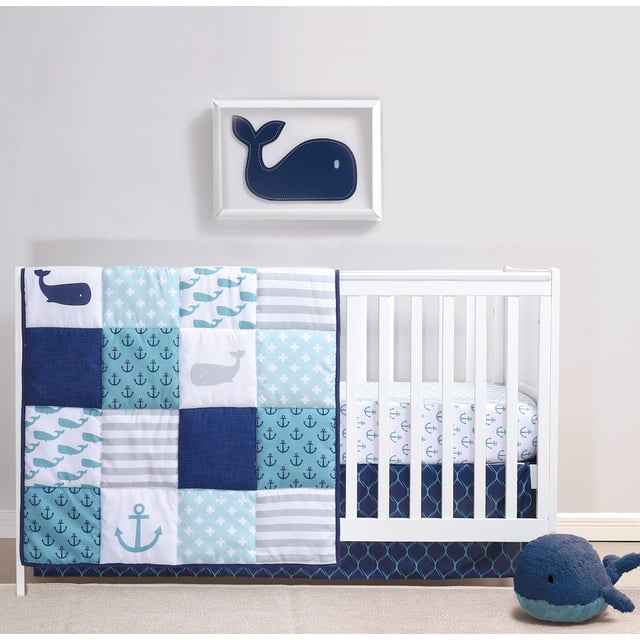 The Peanutshell Nautical Whale Patchwork Crib Bedding Set for Baby Boy, a 3-piece nursery set made of microfiber. Includes a reversible crib quilt with a nautical theme in navy blue, aqua, grey, and white featuring whales, anchors, and stripes, a fitted crib sheet with elasticized edges for a snug fit, and a 3-sided crib skirt. Displayed on a white crib with a matching whale-themed wall art and plush toy.