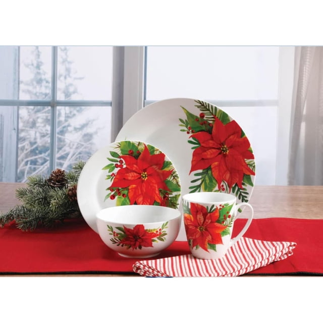 Gibson Home Magic Poinsettia 16 Piece Dinnerware Set in fine ceramic includes 10.75-inch dinner plates, 7.75-inch salad plates, 6-inch bowls, and 12 oz mugs, all decorated with red poinsettia and green leaves for Christmas entertaining, displayed on a wooden table with festive linens and pinecone greenery. This durable set is also suitable for holiday gift giving.