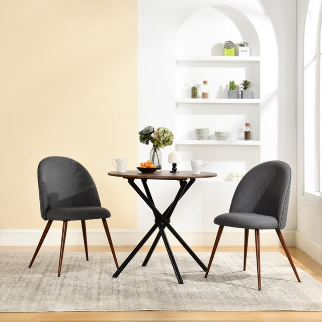Homy Casa set of 2 armless dining chairs in grey fabric with curved upholstered backs and padded seats, supported by tapered wooden legs, paired with a round wooden dining table with black metal legs in a bright kitchen dining space with beige and white walls and built-in shelves, suitable for compact dining areas.