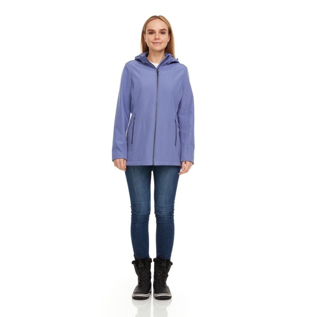 Swiss Tech Veste Coquille Souple à Capuche pour Femme en Bleu Atténué, Vue avant d'Un Modèle Portant un Jean Bleu Foncé et des Bottes d'Hiver Noires, avec une Fermeture Éclair Complète à l'Avant, des Poches à Main Zippées et une Capuche Détachable et Ajustable Idéale pour la protection par Temps Extérieur.