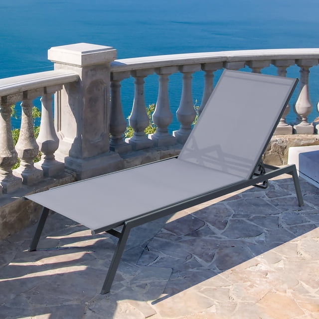 Gymax Chaise Longue de Patio à 6 positions Réglables en Gris, Dotée d'Un Tissu Respirant et à Séchage Rapide avec un Cadre Métallique Robuste. la Chaise Offre six positions de Dossier Réglables, Dont une position Plate pour Bronzer. Conçue pour l'Extérieur, Elle Présente une Finition Antirouille et des Patins Antidérapants pour la Stabilité. Montrée sur un Patio en Pierre Surplombant une Vue Océanique Pittoresque.