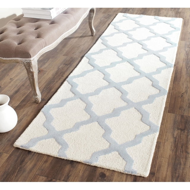 Safavieh Cambridge Liam Geometric Area Rug runner with white wool base and light gray geometric pattern, hand-tufted with plush cut and textured high/low loop piles, displayed on wood flooring beside a tufted bench and white vase, ideal for modern American home or office accent decor.
