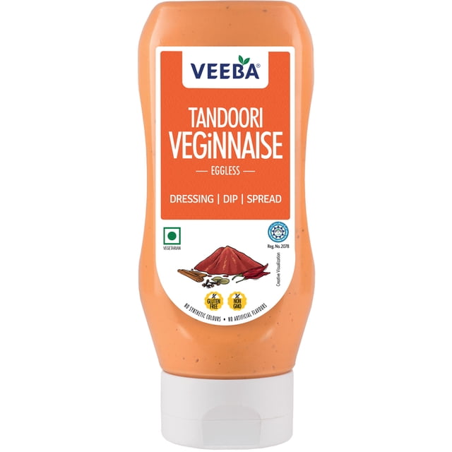 Veeba veginnaise Tandoori Sans Oeufs dans une Bouteille Compressible avec une Étiquette orange Indiquant la Marque et le Nom du Produit, Utilisée comme Vinaigrette, Trempette et Tartinade. l'Étiquette Représente des Épices Tandoori Incluant des Bâtonnets de Cannelle, des Gousses de Cardamome, des Clous de Girofle, du Piment et de la Poudre, et Déclare Sans Gluten, non-OGM, Végétarien, Sans Colorants Synthétiques et Sans Arômes Artificiels. Convient pour Ajouter une Touche