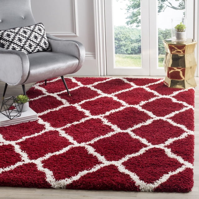 Safavieh Hudson Tapis Shag Géométrique Aliné pour Aire avec Poil Shag Synthétique Peluche Rouge Foncé et Motif de Carreaux Marocains Blanc, Montré sur Plancher de Bois Clair dans une Pièce Lumineuse avec Fauteuil Gris et table d'Appoint Géométrique Dorée, Idéal pour Ajouter Chaleur et texture à la Déco de la Maison.