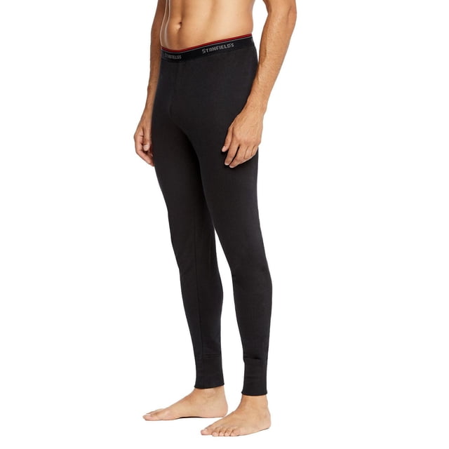 Stanfield's Essentials Double Layer Thermal men's black thermal pants shown in a 3/4 front view on a male model, featuring a close fit with a red-accented elastic waistband branded Stanfield's, made from soft knit fabric with moisture-wicking and antimicrobial properties for superior cold-weather insulation, also suitable for layering under outdoor gear.