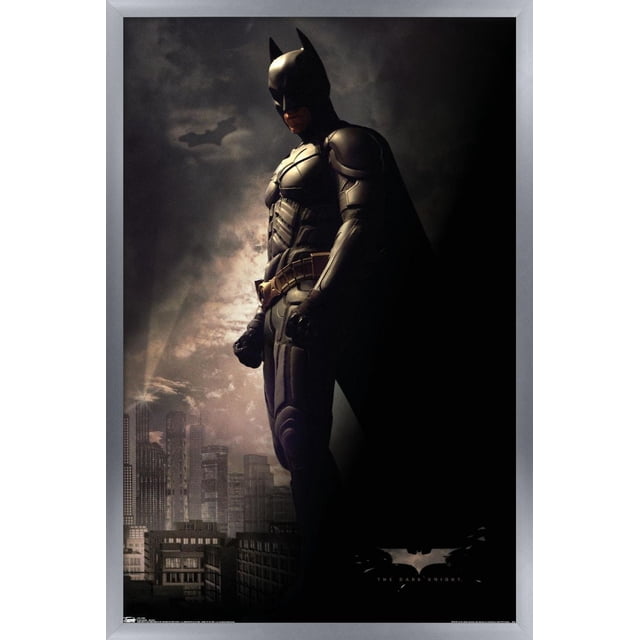 DC Comics Film - The Dark Knight - Batman dans l'Ombre Affiche Murale, 22,375 Pouces x 34 Pouces Affiche Encadrée Montrant Batman en Costume Blindé Noir et cape Debout de Profil contre une Ligne d'Horizon de Ville Sombre avec des Gratte-Ciel Illuminés et un Symbole de Chauve-Souris Projeté dans un Ciel Nocturne Nuageux, Convient à la Décoration Murale de la Maison Ou du Bureau.
