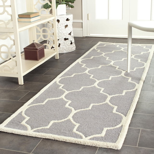 Safavieh Cambridge Kevin Geometric Area Rug in grey with white geometric trellis pattern, hand-tufted wool with plush cut and high/low loop pile, displayed on dark tile flooring in a bright room with white furniture, ideal for adding modern American style to home or office decor.