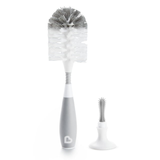 Munchkin Bristle Bottle Brush, Grey, with a standing design featuring a textured grey non-slip handle and white nylon bristles, accompanied by a soft rubber nipple brush with suction cup base for sanitary drying, suitable for cleaning baby bottles and accessories.