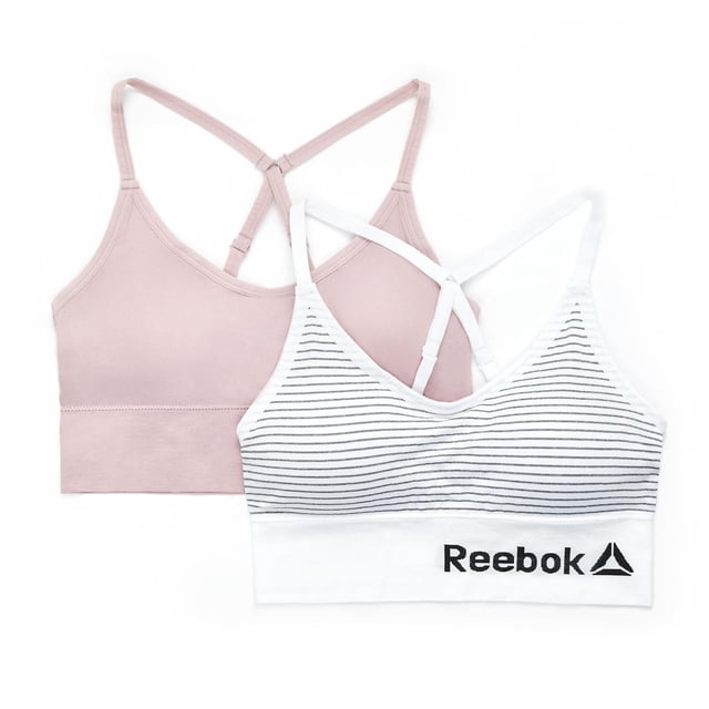 Reebok Ladies' 2 Pack Seamless Longline Bralettes including one solid light pink and one white with thin black horizontal stripes, both with adjustable racerback straps and longline bands for a smooth fit, the striped bralette featuring the black Reebok logo on the band, ideal for yoga or training.