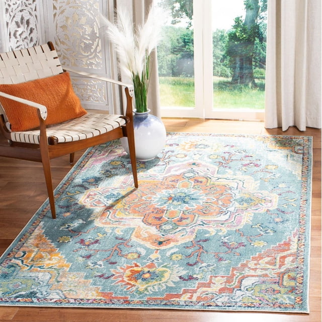 SAFAVIEH Crystal Tapis Floral Debra avec une Laine Synthétique Tissée Mécaniquement à Poils Courts et un Motif de Médaillon Floral Complexe dans des Tons Bleu, orange et Jaune, Posé sur un Plancher de Bois Franc à Côté d'Une Chaise en Bois de Style Mi-Siècle Moderne avec des Sangles Tressées Blanches et un Coussin orange, à Côté d'Un vase en Céramique Bleu et Blanc avec Herbe de la Pampa, dans une Pièce Ensoleillée avec des Portes en Verre et des Rideaux Beiges, Idéal pour les Salons Ou Salles à Manger Transitionnels.