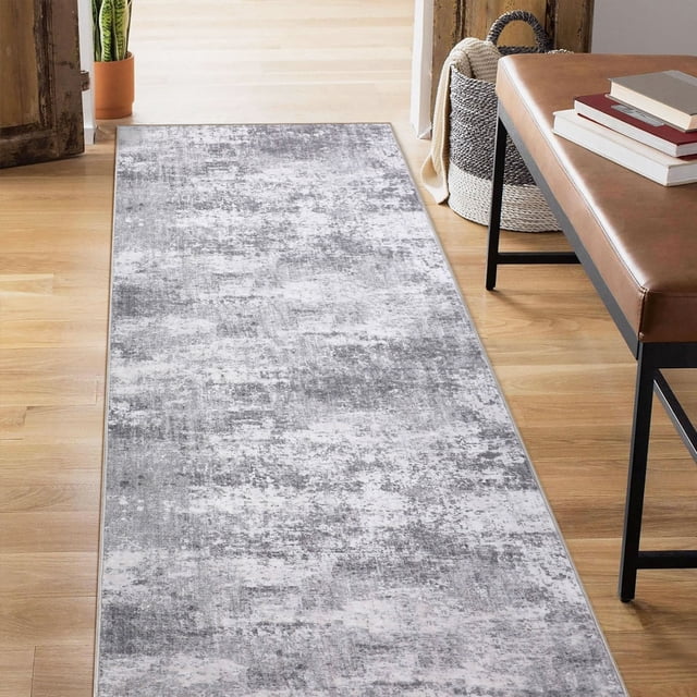 BERTHMEER 2'x6' Abstract Hall Runner Rug in gray, showcasing a modern abstract design with a low-pile height of 0.2 inches. Crafted from polyester and thermoplastic rubber for durability, non-slip functionality, and machine washability. Suitable for hallways, entryways, or offices. Displayed in a bright indoor setting with wooden flooring and adjacent furniture.
