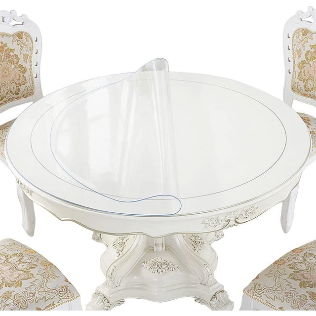 GFDYREE 42 Inch Round Clear Plastic Dining Table Protector made of PVC material shown on a white round dining table with ornate detailing. The transparent, waterproof, and wipeable tablecloth cover is partially rolled back to display its thickness and clarity. Suitable for protecting wooden, glass, or marble surfaces from scratches, spills, and heat up to 176°F (80°C).