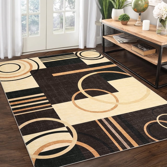 Garvee Modern Geometric Area Rugs 8'x10' in brown, featuring an abstract geometric design with circles and stripes. This washable, non-slip, low-pile throw carpet is made from 100% polyester with TPR backing, offering stain resistance and fade resistance. Suitable for living rooms, dining rooms, or bedrooms, shown in a cozy indoor setting with wooden floors and natural light.