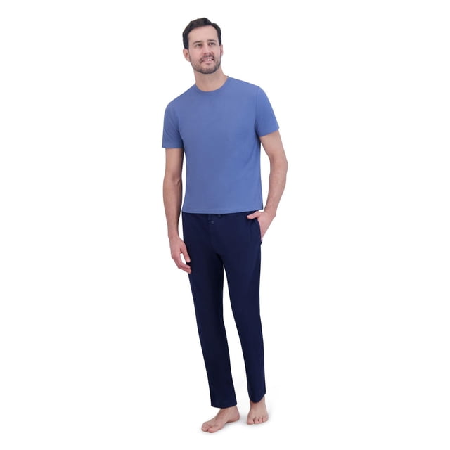 HANES KNIT PJ SET with a male model wearing a blue short sleeve crew neck knit top and navy blue knit pants featuring a button fly and side pockets, standing barefoot on a white background, crafted from breathable cotton blend fabric with a tagless design, ideal for year-round men's sleepwear comfort.