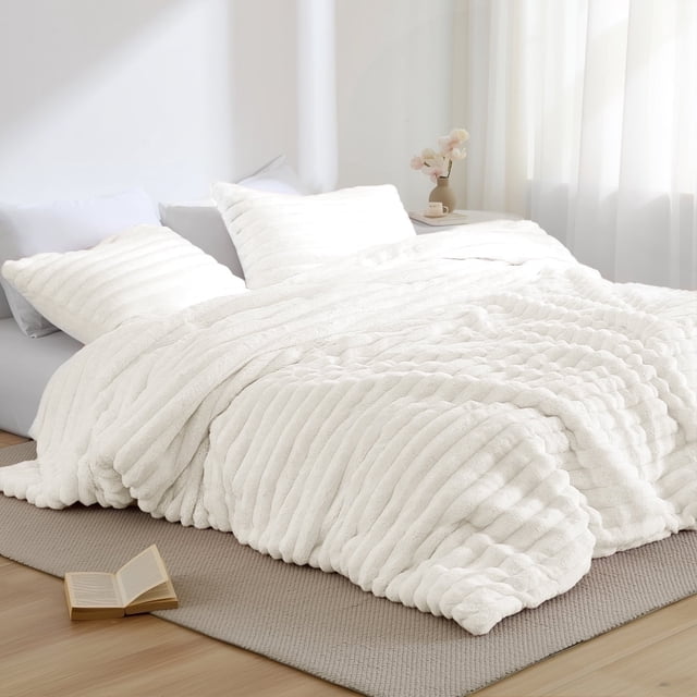 Regency Heights Full/Queen Size Comforter Set, a 3-piece bedding set in ivory, featuring a fluffy ribbed plush texture with a soft mink reverse. The set includes a 90-inch by 90-inch comforter and two 20-inch by 26-inch shams with overlapping enclosures for secure pillow placement. Made with premium 300 gsm fabric for added weight, softness, and warmth, this Oeko-Tex certified set ensures safety and gentle skin contact. Displayed in a bright, minimalist bedroom with natural light and a neutral-toned rug.
