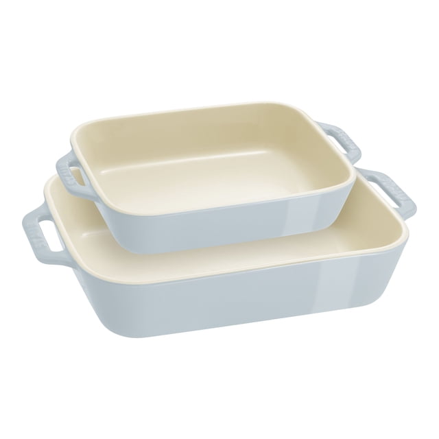 STAUB Ceramique Rectangular Baking Dish Set Light Blue 2 Piece featuring two ceramic baking dishes with a vitreous porcelain-enamel finish. The set includes a smaller dish measuring 20 x 16 cm with a 1.1-liter capacity and a larger dish measuring 27 x 20 cm with a 2.4-liter capacity. Both dishes have a light blue exterior, cream interior, and double handles for easy maneuvering. Designed for baking lasagna, casseroles, desserts, and roasting meats or vegetables, these dishes are microwave, freezer, broiler, and oven safe up to 300°C/570°F. Dishwasher and metal utensil safe, they transition beautifully from oven to table.