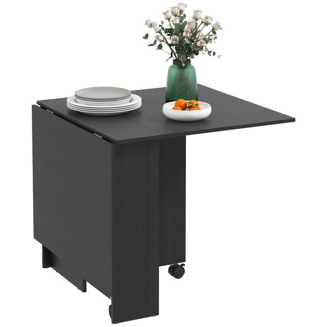 HOMCOM Foldable Dining Table with Storage Shelves, Drop Leaf, and Wheels in black. The table features a modern design with a drop-leaf mechanism for adjustable size, accommodating up to six people when fully extended. It includes two-tier shelves for discreet storage and wheels with brakes for easy mobility and stability. Made of durable particleboard with a melamine-coated top for easy cleaning. Shown partially extended with plates, a bowl of fruit, and a vase of flowers on top.
