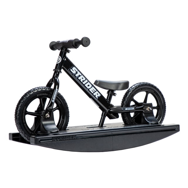 Strider - 12 Sport 2-in-1 Rocking Bike in black, designed for children aged 6 months to 5 years. The bike is securely mounted on a black rocking base, featuring a lightweight frame, padded seat, and toddler-sized grips. The no-tool adjustable seat and handlebar, along with never-flat tires, make it suitable for growing children with an inseam of 22-51 cm (8.75-20 in.).