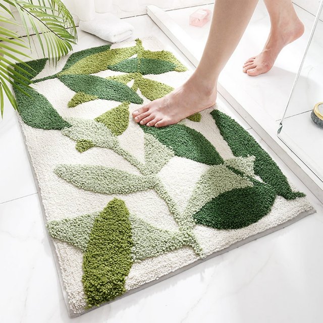 SDOTXA Clearance!!! Green Leaves Bath Mat featuring a non-slip design with a large monstera leaf pattern in various shades of green on a white background. This absorbent and plush bathroom rug is shown placed on a white tiled floor near a shower, with a person stepping onto it. Ideal for adding a touch of nature to bathroom decor.