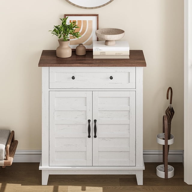 Buffet – Armoire de Rangement Style Ferme Moderne avec Tablettes Réglables à 3 Niveaux et Tiroir, Présentant une Finition Contrastante en Bois Blanc Vieilli et un Dessus Brun. Idéale pour le Rangement de Cuisine, l'Organisation de la Salle à Manger Ou l'Entrée. l'Armoire Est Conçue avec des Articles Décoratifs comme un vase, des Livres et un Bol sur Sa surface, Illustrée dans un Décor d'Entrée Chaleureux.