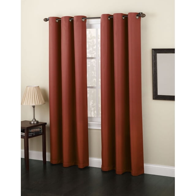 Rideaux à Oeillets N° 918 de Montréal de Couleur Rouille, Lot de Deux Panneaux Assombrissants de 48 par 95 Pouces avec Oeillets Métalliques sur Tringle Noire dans une Pièce beige avec Plancher de Bois Franc Foncé, à Côté d'Une table d'Appoint en Bois avec une Lampe et des Livres, Convenant aux Habillages de Fenêtre de style Décontracté.