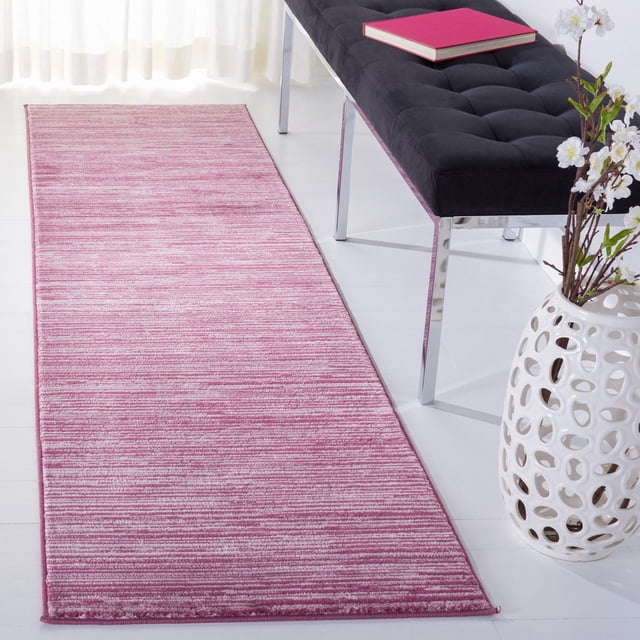 Safavieh Vision Adrasteia Overdyed Solid Area Rug in pink and white tones with a subtle striped texture, laid as a runner on a white floor beside a black tufted bench with chrome legs and a red book, next to a white decorative vase with floral branches, ideal as an accent rug for modern living rooms.