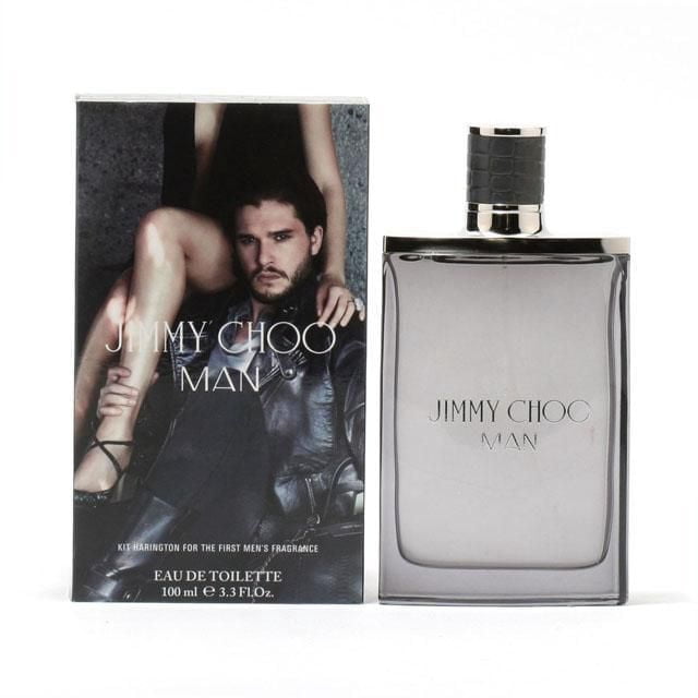 Jimmy Choo Eau De Toilette Spray For Men 100ml showing a rectangular smoky glass bottle with silver edges and a black textured cap, next to its box featuring a man in a leather jacket and a woman's legs, highlighting a modern aromatic fruity men's cologne.