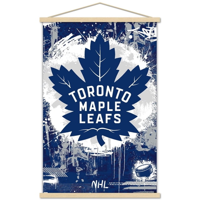 NHL Toronto Maple Leafs - Maximalist Logo 23 Wall Poster with a large navy blue maple leaf featuring white veins and bold white text 'TORONTO MAPLE LEAFS' centered on a blue and gray graffiti-style background, printed on glossy paper with wooden frame hangers, measuring 22.375 by 34 inches, suitable for sports-themed wall décor in bedrooms, offices, or dorms.