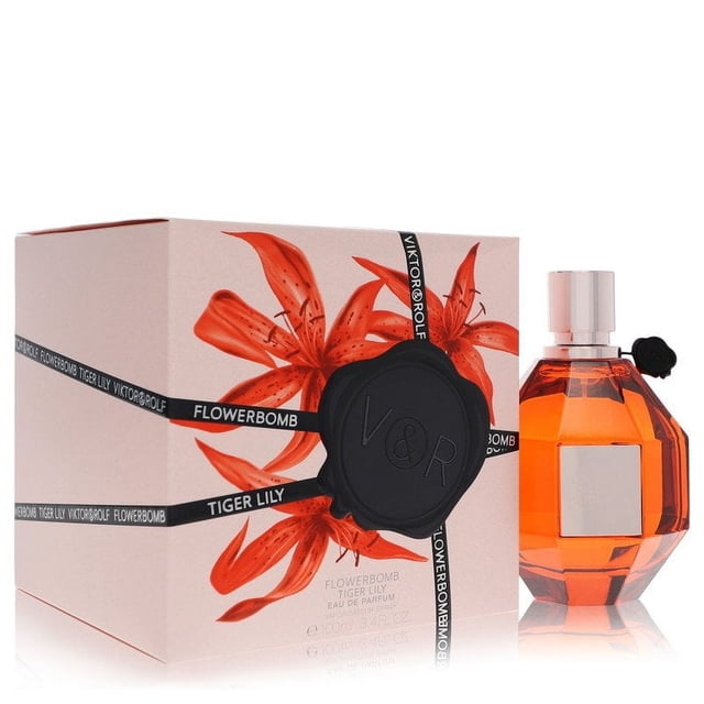 Flowerbomb Tiger Lily by Viktor & Rolf Eau De Parfum Spray for Women, 3.4 oz bottle. The fragrance features a blend of coconut milk accord, tiger lily accord, mango accord, and benzoin. The image shows the perfume bottle with a faceted orange design and a silver cap, alongside its packaging adorned with vibrant tiger lily graphics and the Viktor & Rolf logo.