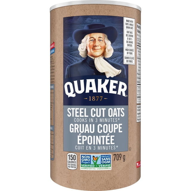 Quaker Quick Cook Steel Cut Oats in a 709 g cylindrical container featuring the Quaker logo with a man in a black hat and white scarf, labelled to cook in 3 minutes, non-GMO verified, 150 calories per serving, ideal for quick oatmeal or baking recipes.
