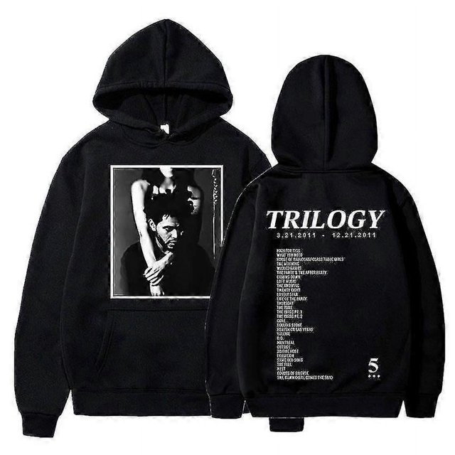 Chandail à Capuchon Graphique de Musique The Weeknd Trilogy en Tissu polyester Noir. l'Avant Présente un Graphique monochrome d'Une Personne aux Bras Croisés, pendant Que l'Arrière Affiche le Texte « Trilogy » avec des dates et une Liste de Titres de Chansons. Conçu avec un Capuchon et des Manches Longues.