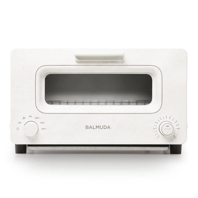 BALMUDA The Toaster, a compact steam oven toaster in white, designed with steam technology and precise heat control. It features five cooking modes for sandwich bread, artisan bread, pizza, pastry, and oven use. The front-facing view highlights its clean design, baking pan, and temperature regulation for optimal texture and flavor.