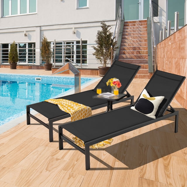 Gymax Ensemble de 2 Chaises Longues de Patio Réglables en Noir, avec un Cadre en Aluminium Léger et des Dossiers Réglables à 6 Positions. les Chaises Sont Positionnées au Bord de la Piscine sur une Terrasse en Bois, avec une Chaise Accessoirisée avec un Jeté à Motif Jaune et un Coussin Décoratif. la Conception en Tissu Respirant Assure Confort et Durabilité, Convient à une Utilisation Extérieure dans Divers Contextes.