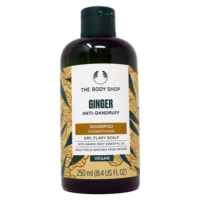 The Body Shop Anti-Dandruff Ginger Shampoo 8.4 ounces bottle with a dark amber container and flip-top cap. The label highlights ginger root essential oil for dry, flaky scalp, Community Trade honey from Ethiopia, and vegan formula. Anti-dandruff shampoo designed to soothe and nourish hair.