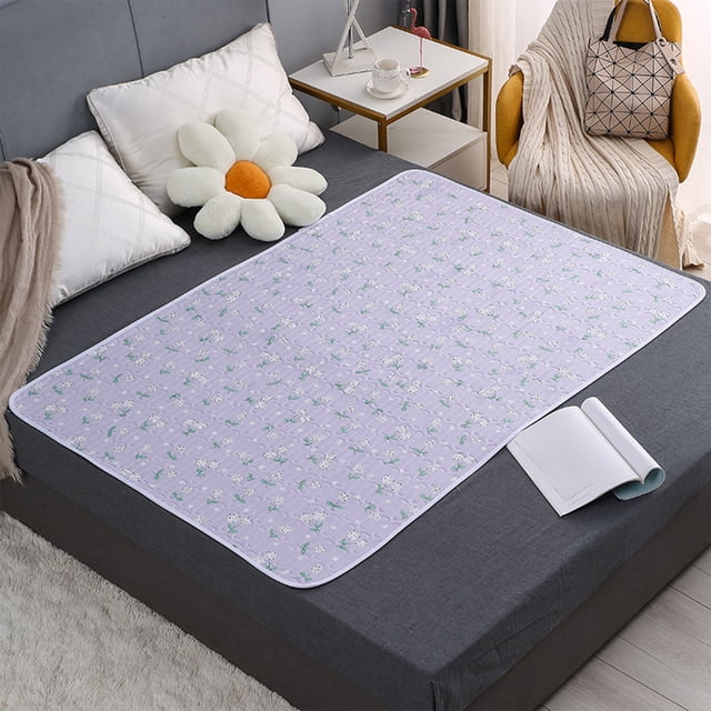 59x39.37 inches waterproof and washable nursing pad for elderly care, incontinence protection, menstrual use, and child bedwetting. The pad features a multicolor floral design, multi-layer protection with waterproof and anti-slip layers, and is suitable for use as a mattress topper. Displayed on a grey bed in a modern bedroom setting.