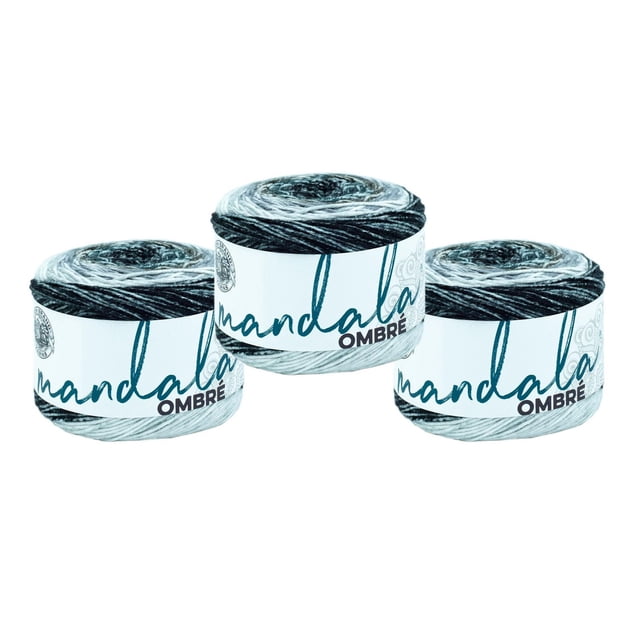 Lion Brand Mandala Ombre Yarn - Harmony showing three skeins of thick acrylic yarn with a gradual blend of black, gray, and cream colors in an ombré pattern, wrapped in white labels with the product name, suitable for knitting, crochet, and other yarn crafts.