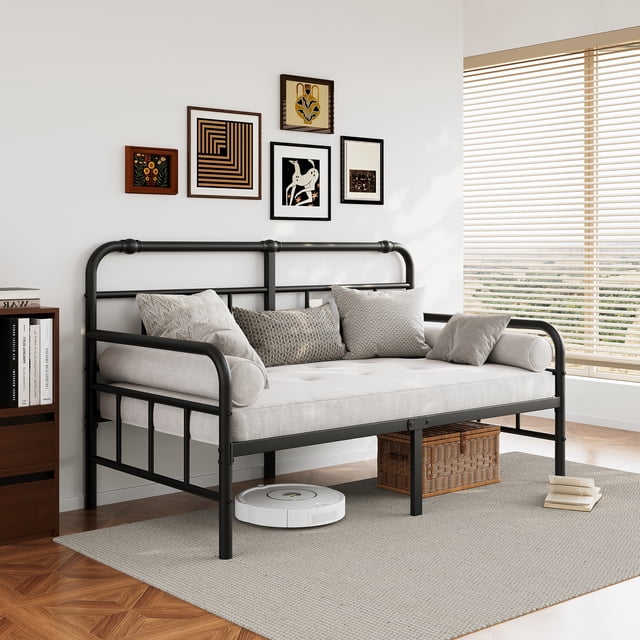 FSCHOS Cadre de Lit de Jour en Métal de 14 Pouces Format Simple Montré dans un Décor de Salon Moderne. le Cadre en Métal Noir Présente des Accoudoirs Arrondis pour la Sécurité et le Confort, avec un Coussin Ton Neutre et des Oreillers Décoratifs. le Lit de Jour Offre une Double Fonctionnalité comme Canapé et Lit, avec un Grand Espace de Rangement sous le Lit visible, Incluant un Panier en Osier et un Aspirateur Robotique. le design Épuré Complète le Décor Minimaliste, Incluant de l'Art Mural et la Lumière Naturelle Provenant de Grandes Fenêtres.