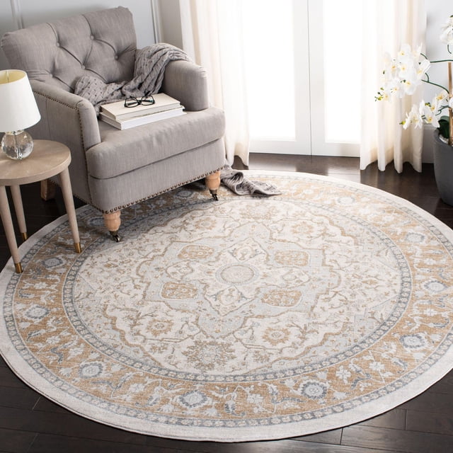 SAFAVIEH Isabella Patrick Tapis à Bordure Florale, Rond avec Médaillons Floraux et Bordures Ornées dans des Tons Gris et beige Doux, Fil Synthétique Tissé Mécaniquement à Poil Mi-Haut, Placé sur Plancher de Bois Franc Foncé sous un Fauteuil Capitonné Gris à Côté d'Une Petite table Ronde avec Lampe, Rideaux Près du Voile et Orchidées Blanches, Convient à une Déco Traditionnelle Ou Chic-Décontractée et Est Souvent Utilisé comme Tapis d'Accent Décoratif.