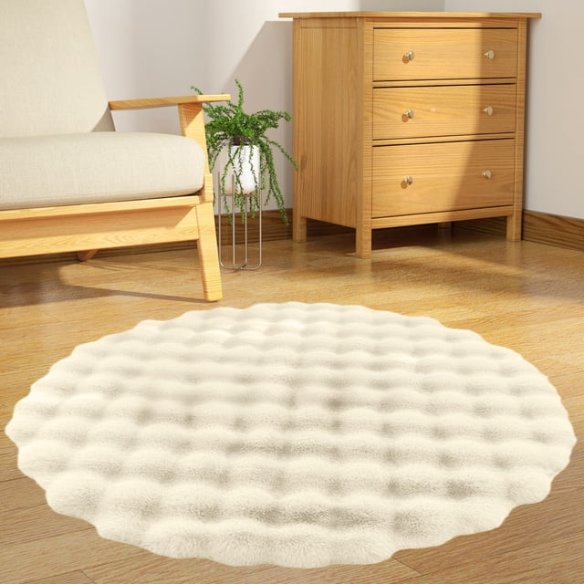 Rkxzt Round Area Rugs Bedroom Rug Soft Plush Fluffy Round Rug in a cream color, measuring 23.62x23.62 inches. The rug features a modern design with high, medium, and low velvet rings for added texture and visual appeal. Made of polyester fiber, it offers a soft feel, durability, and easy maintenance. The slip-resistant bottom ensures stability on various surfaces. Displayed in a cozy living room setting with wooden furniture and a potted plant.